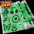 Glow-in-the-dark temporary tattoos displayed on a sheet and two rolls against a black background, featuring designs like a butterfly, turtle, sunflower, astronaut, smiley face, and tropical leaves. A red and yellow promotional badge in the top left reads 'AS LOW AS $4.